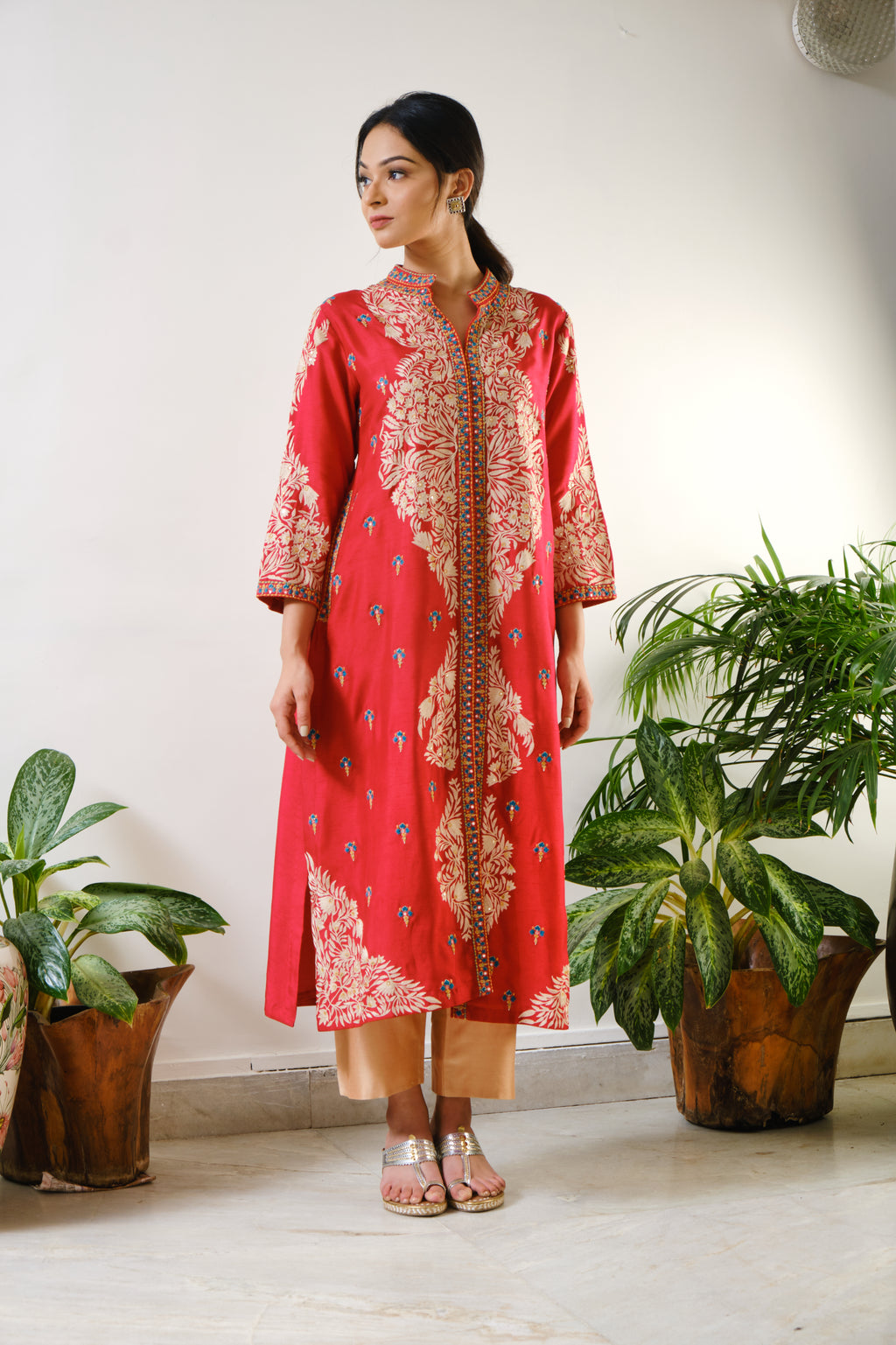 This red dupion silk, chinese collared, 3/4th sleeved, front open jacket with side pockets has delicate ari-mirror embroidery in the centre & sleeves along with a butta at the back.Red embroidered jacket with ari-mirror embroidery